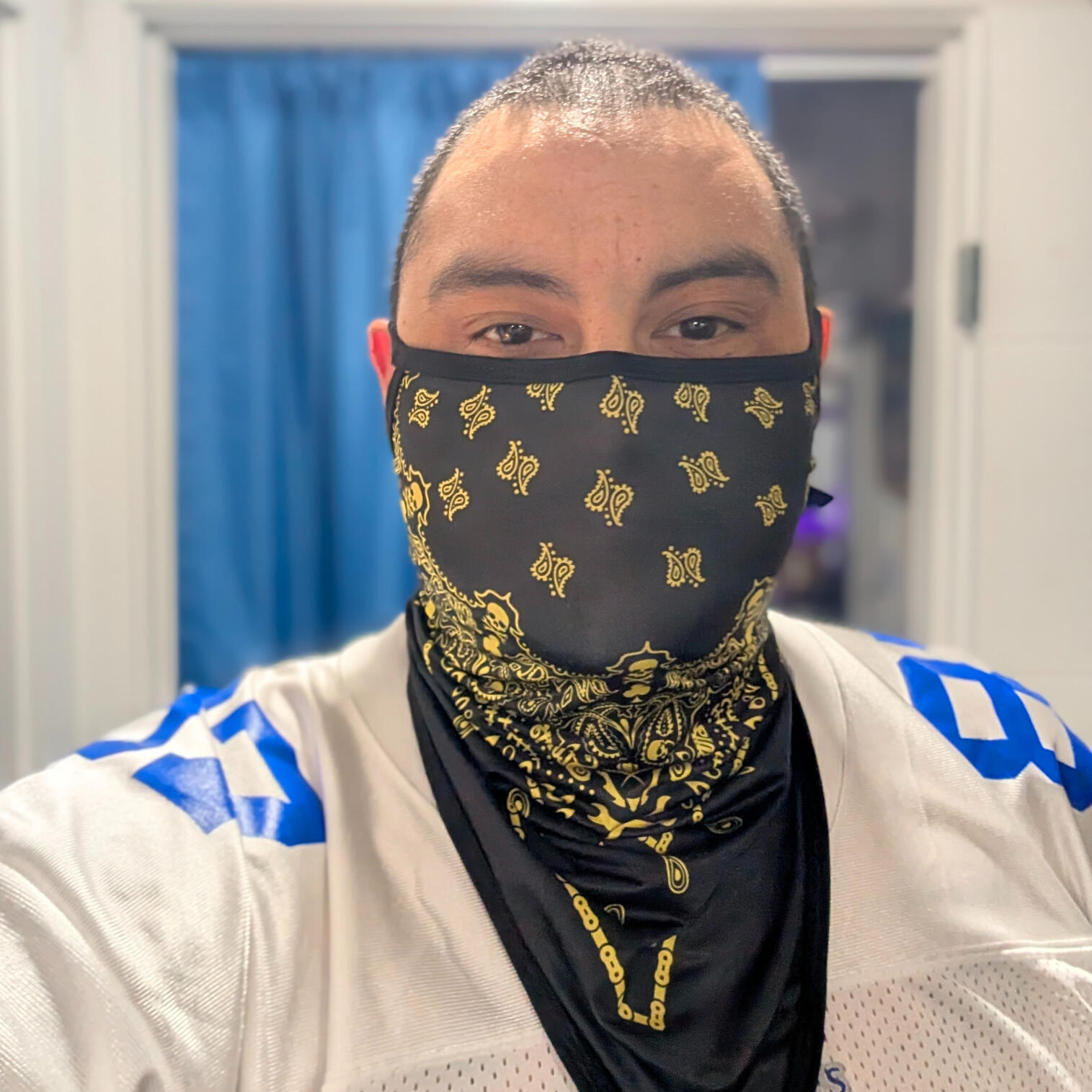 Image of The architect and creator of Barrio Conscious Spiritualism. He is wearing a black and yellow bandana covering his face and is wearing a football jersey #87
